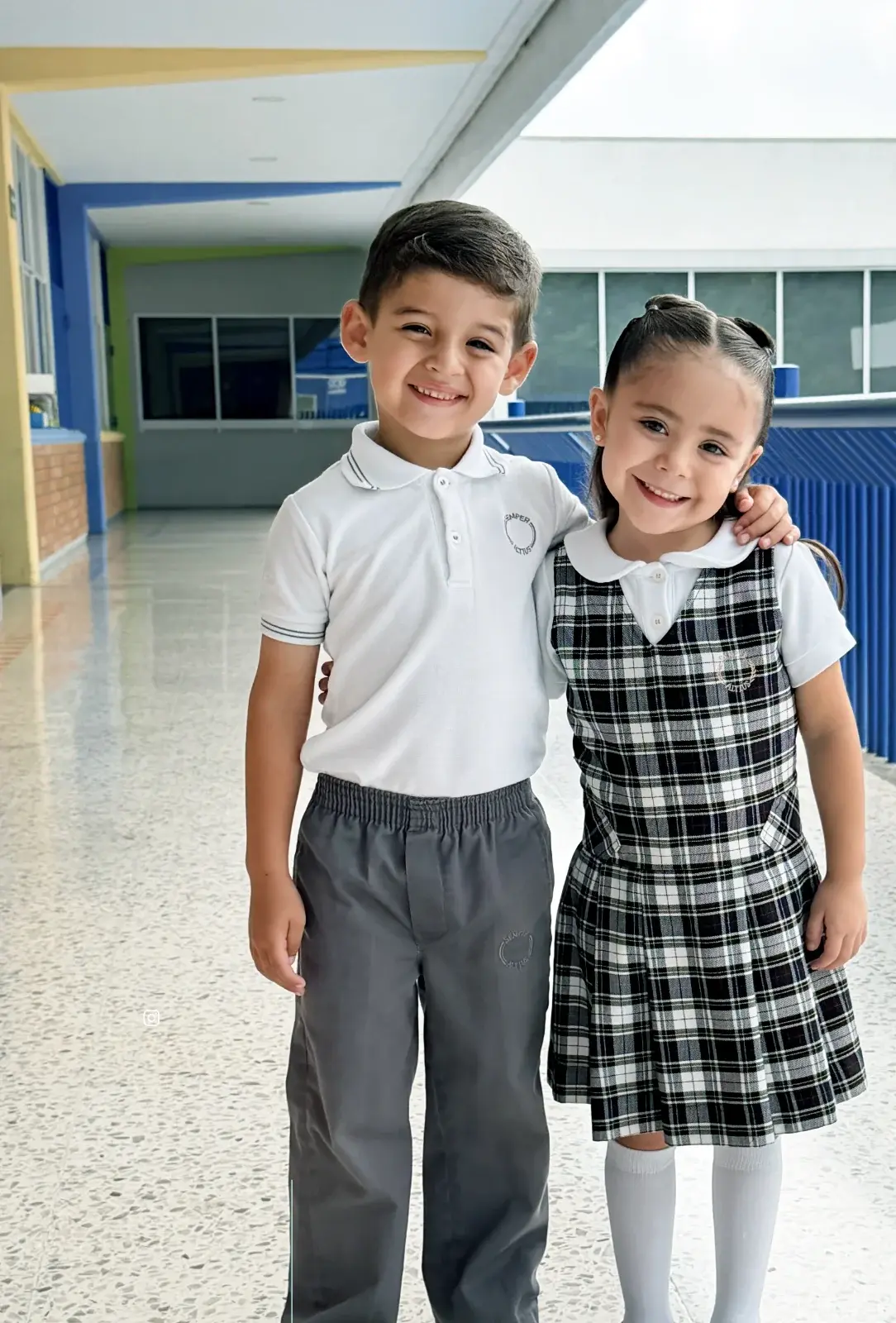 Estudiante sonriente en uniforme escolar durante evento escolar con compañeros de fondo
