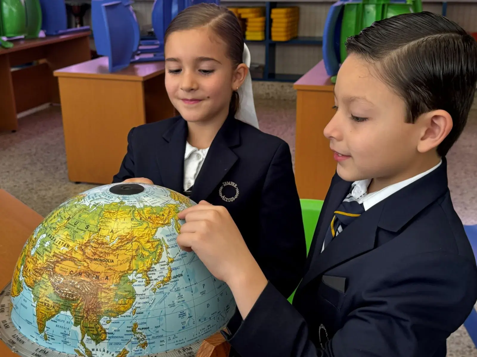 Estudiantes de uniforme escolar exploran un globo terráqueo en el aula durante una lección de geografía.