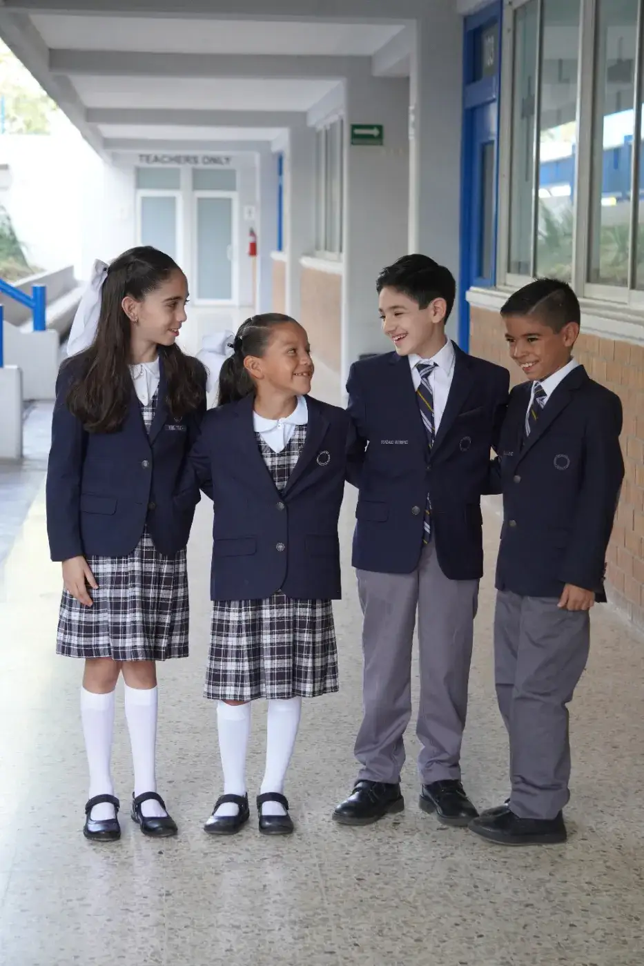 Cinco estudiantes de uniforme escolar sonriendo juntos en el aula durante una actividad grupal
