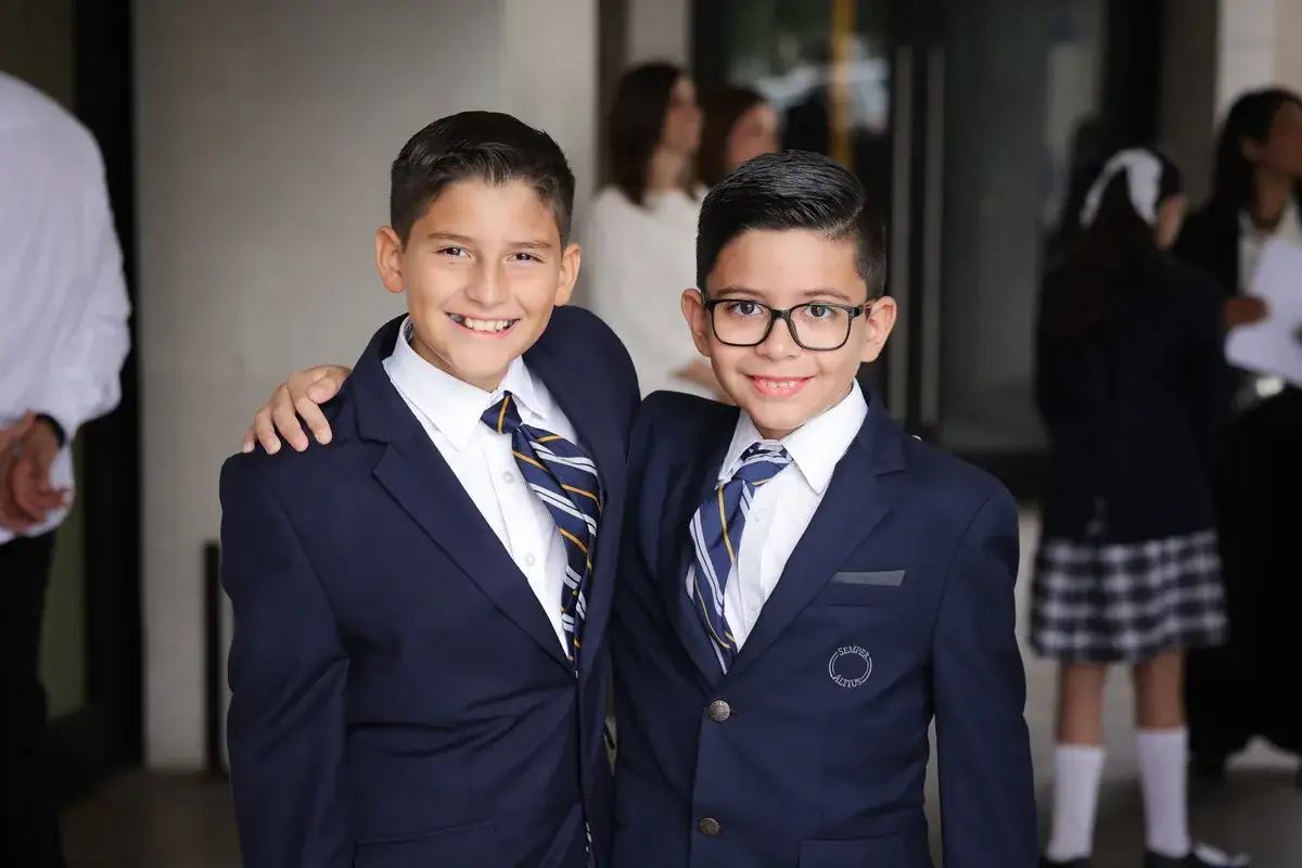 Cuatro estudiantes en uniforme escolar posando en cancha deportiva del colegio